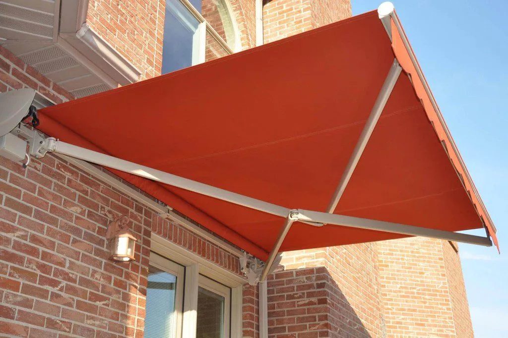 An orange cross arm kit retractable awning fixed into place outdoors