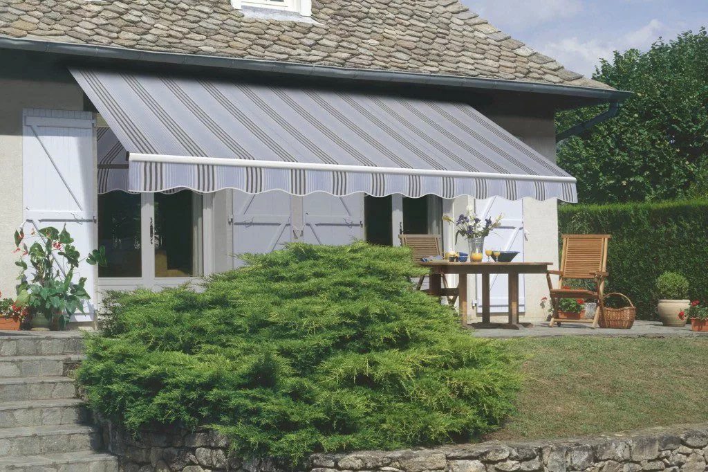 A gray striped retractable awning over a set of windows
