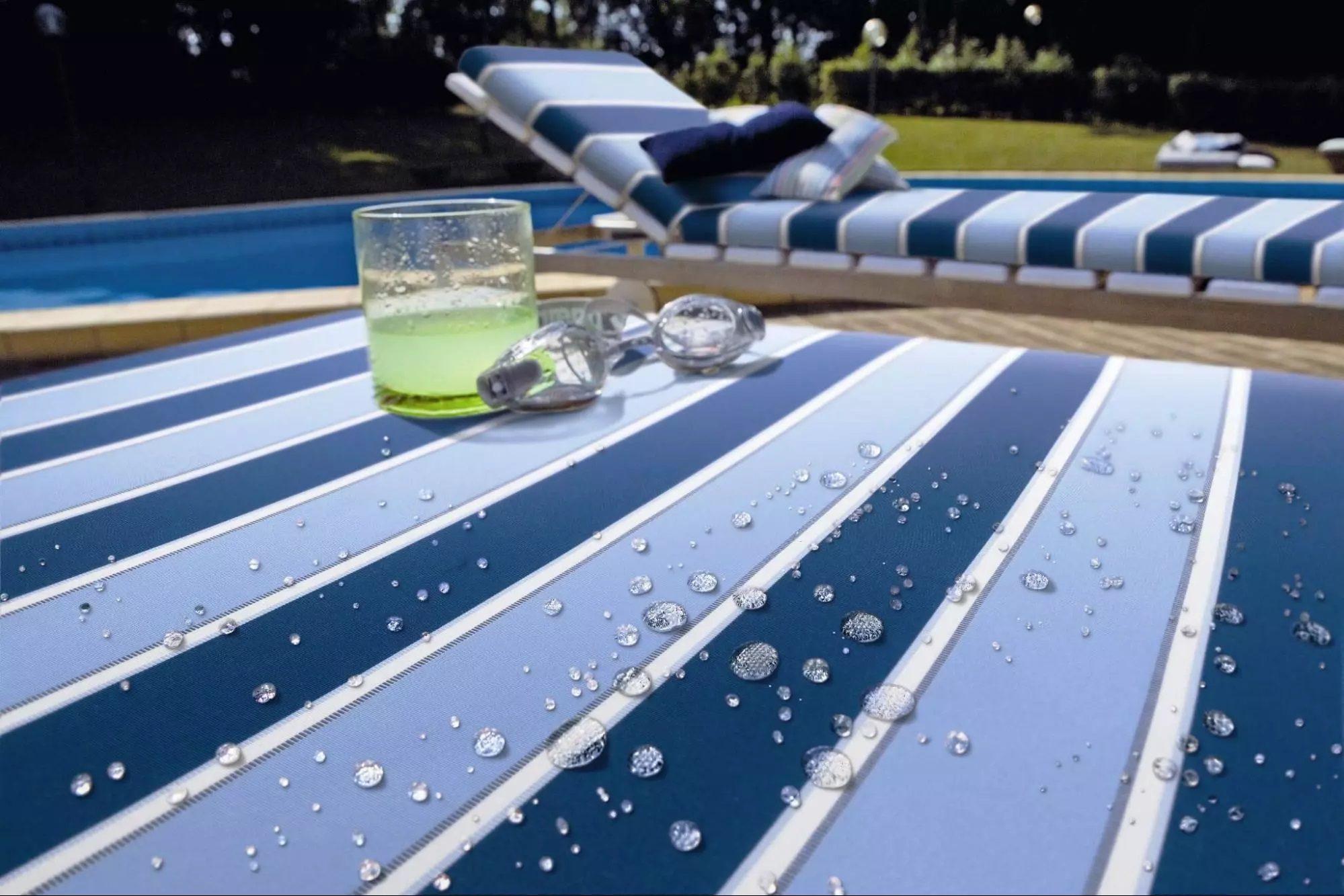 Water-resistant solution-dyed acrylic fabric with droplets of water near a pool